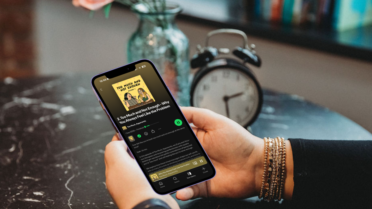 Alice holding a phone showing the podcast Too Much Apparently on Spotify